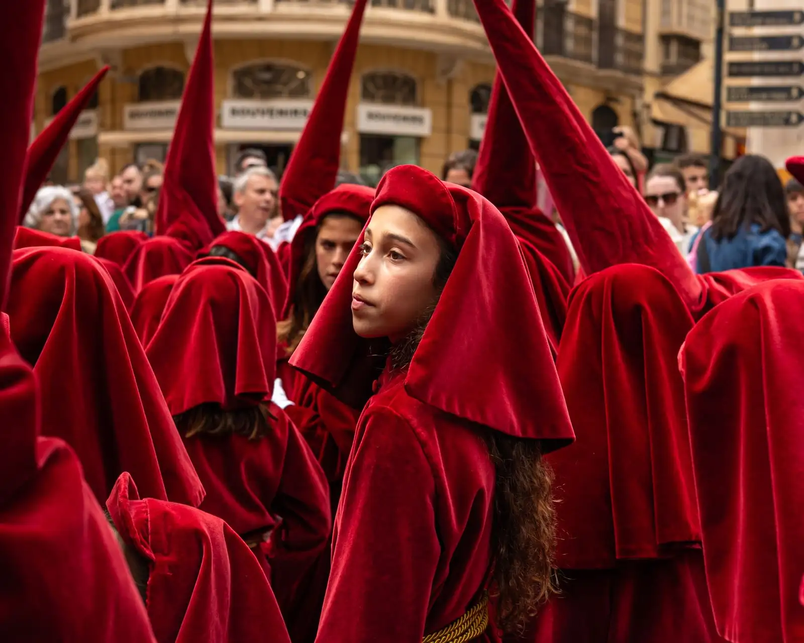 Young participants in red robes during a religious procession in Málaga, Spain.