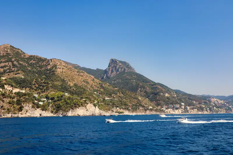 Three speedboats race on blue waters along the picturesque Positano coast, Italy.