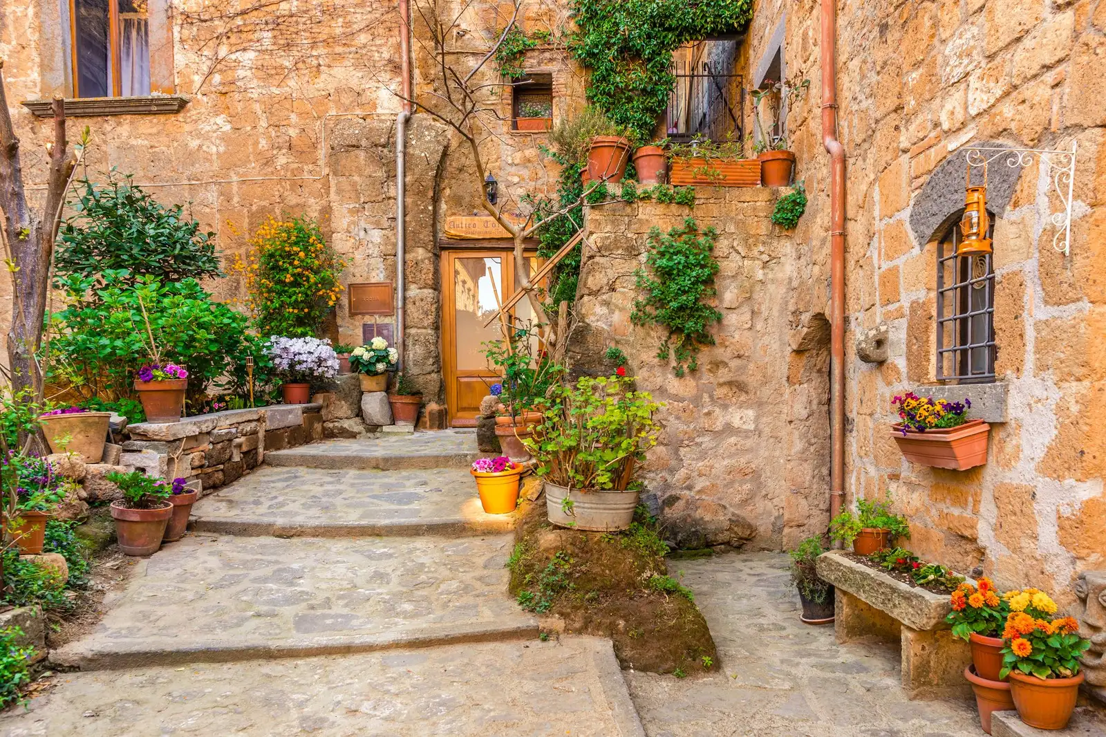 A picturesque medieval alley in Italy adorned with vibrant flowers and rustic stone walls.