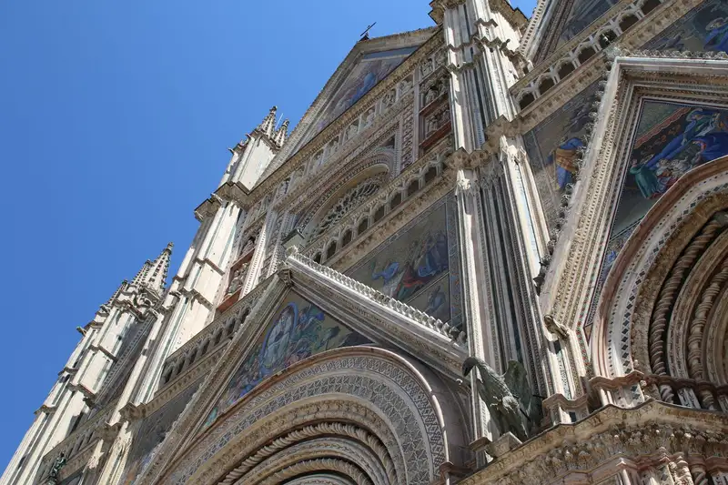 Close-up of the ornate facade of Orvieto Cathedral in Umbria, Italy, showcasing Gothic architecture and intricate mosaic art.