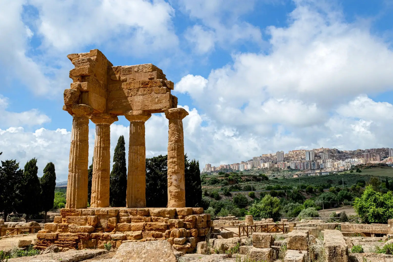 Scenic view of ancient temple ruins and Agrigento city skyline in Sicily, Italy.