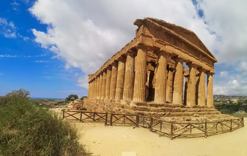 Stunning view of an ancient Greek temple ruin under a bright blue sky in Agrigento, Sicily.